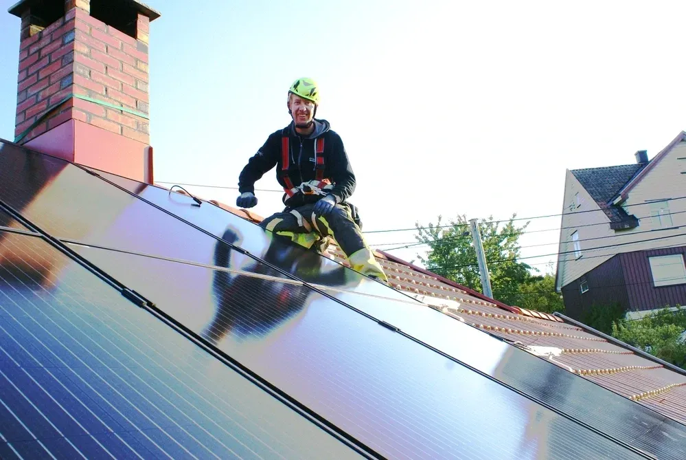 Installateur auf Dach mit Solaranlage